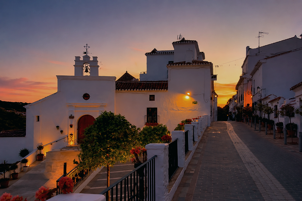 Ruas brancas de Mijas Pueblo, na província de Málaga, com ermida caiada e casario na encosta da Sierra de Mijas ao anoitecer